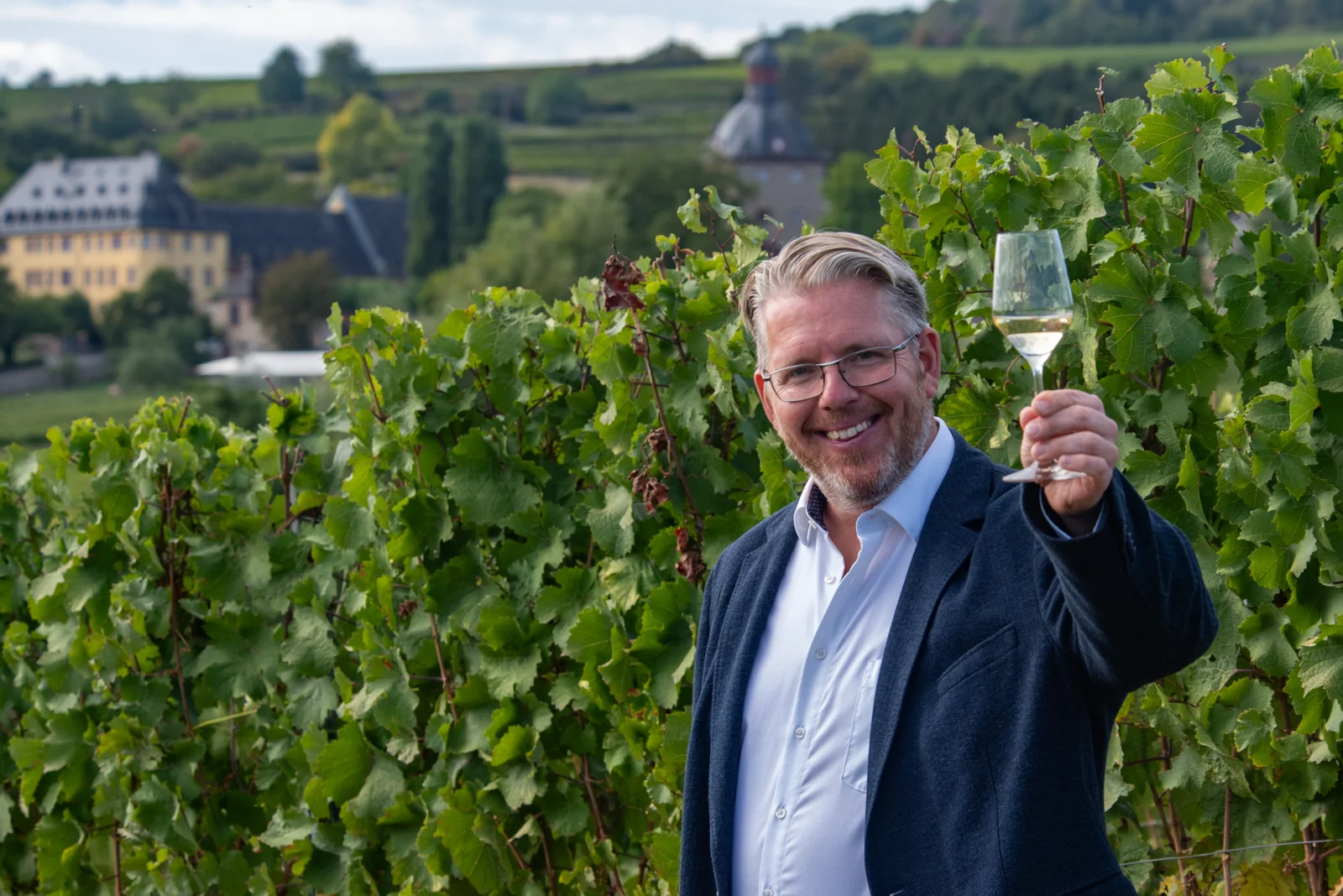 Benjamin Gillert begrüßt seine Gäste mit einem Glas Wein im Weinberg